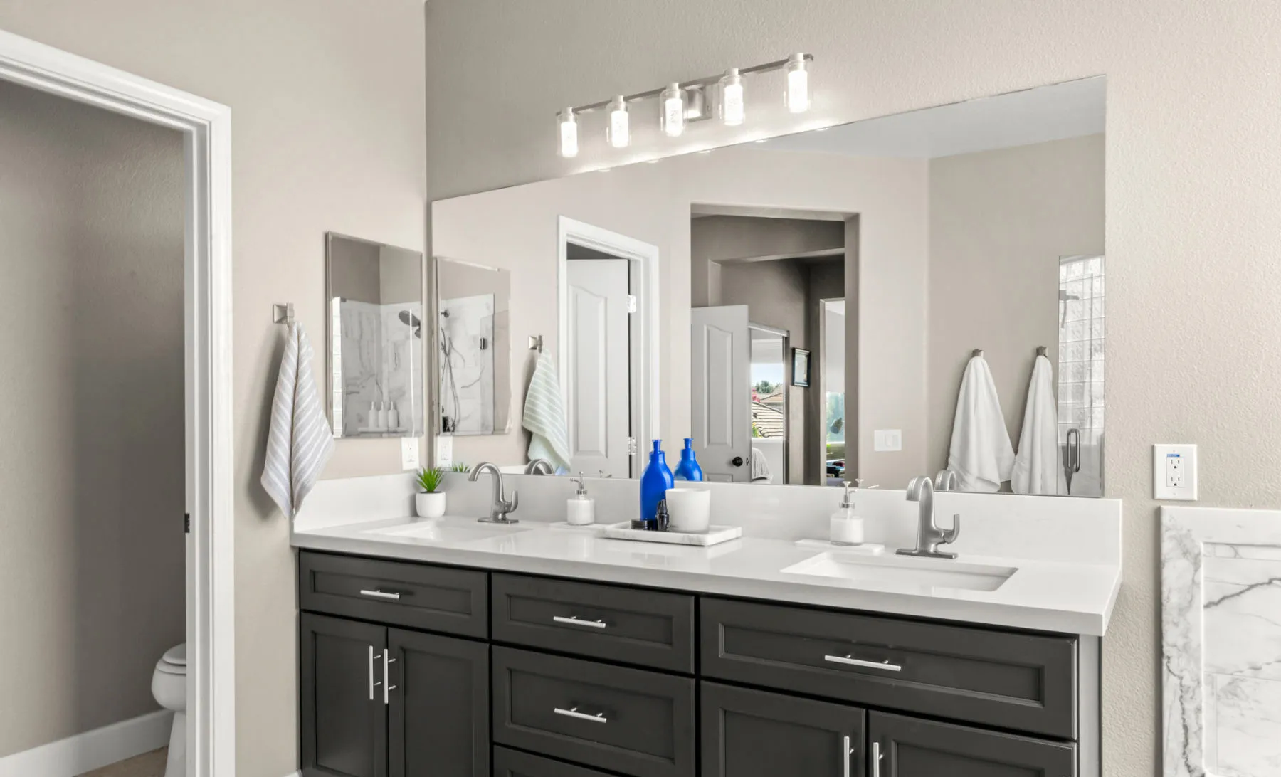 Black double vanity with a long wall mirror and brushed metal fixtures