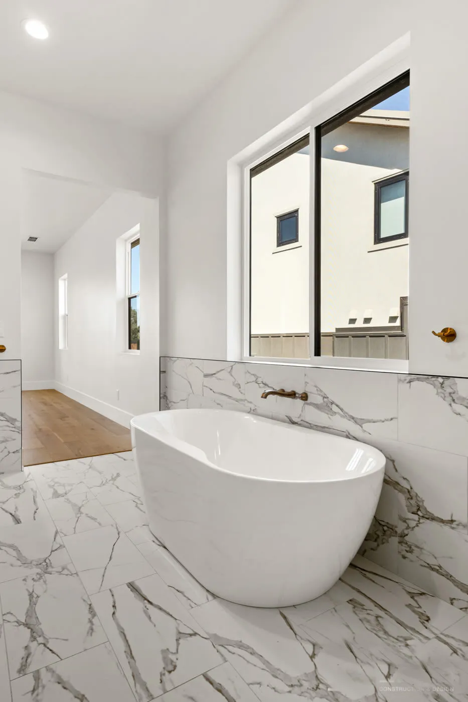 Portrait view of the freestanding tub beside a black-trimmed window