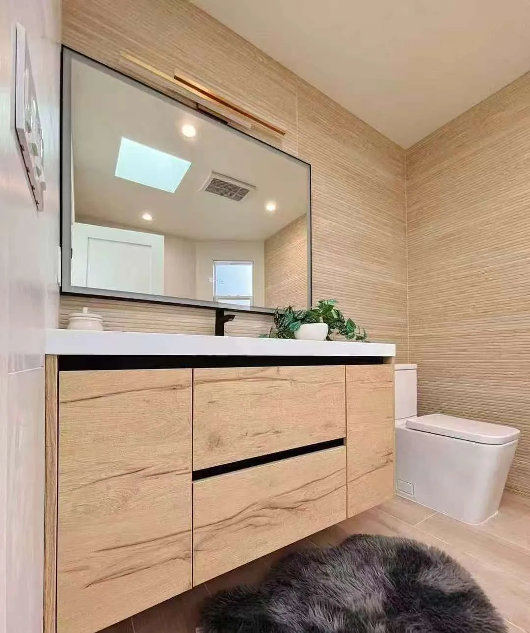 Close view of the light oak vanity, rectangular mirror, and toilet