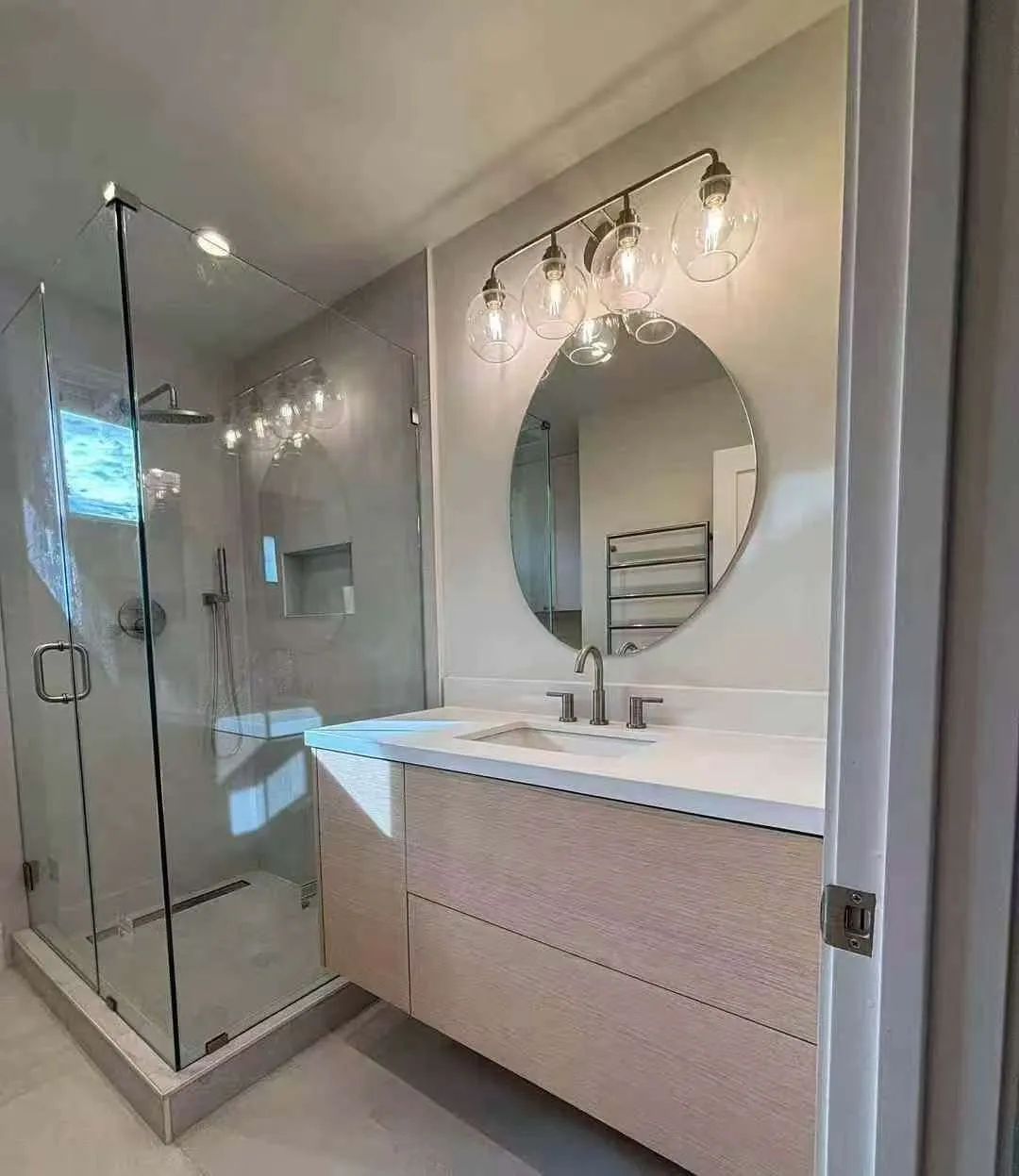 Doorway view of the light oak vanity and glass shower