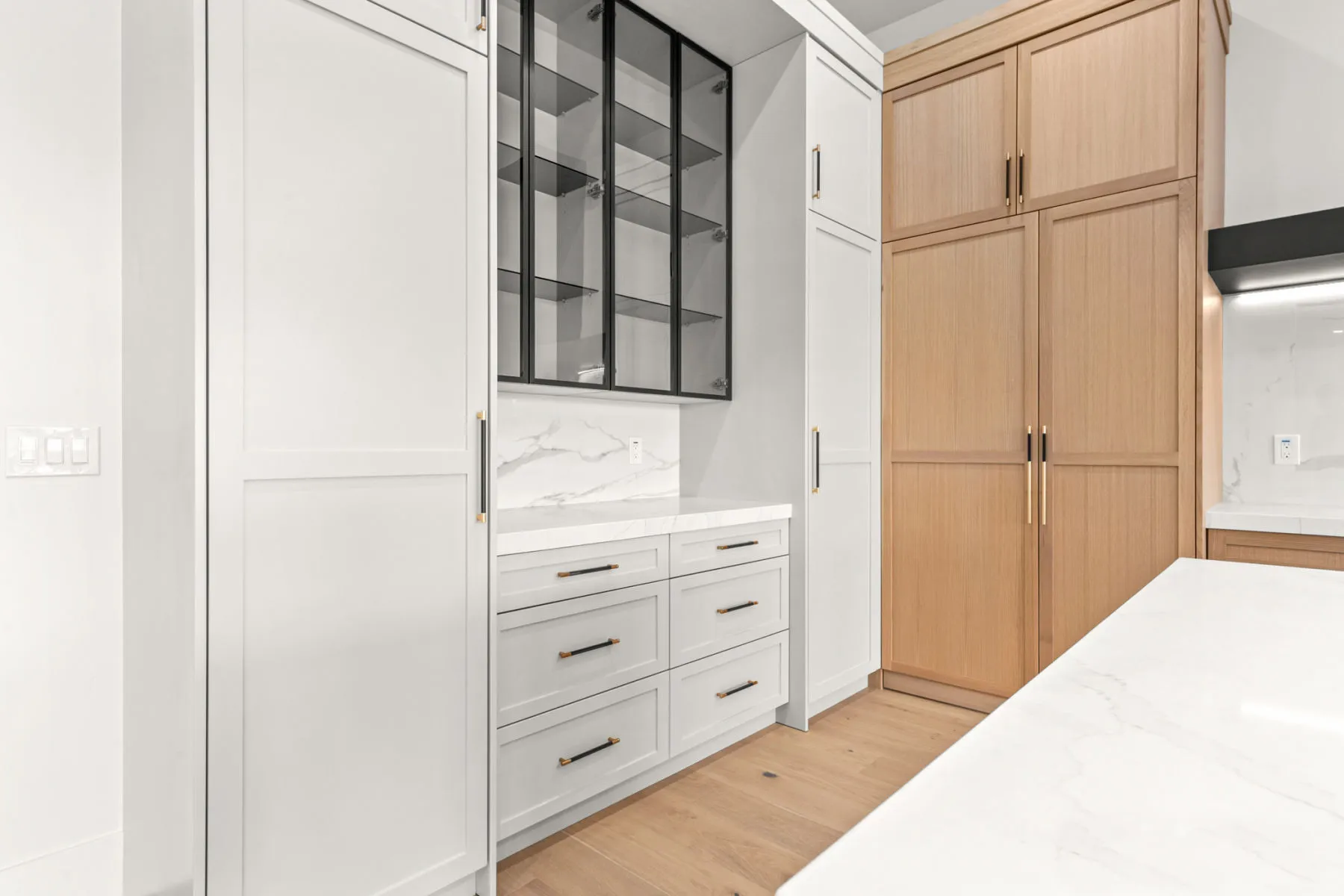 White and oak cabinet wall with a black-framed glass display cabinet
