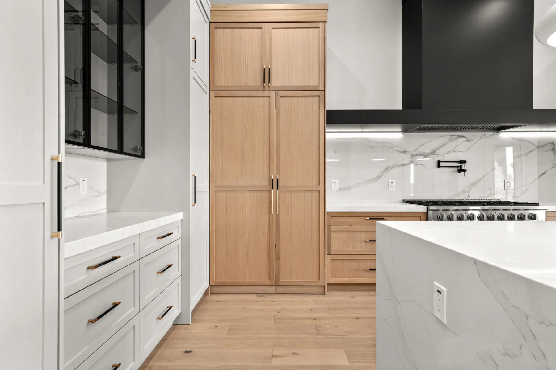 Oak pantry cabinets beside the range and white island countertop